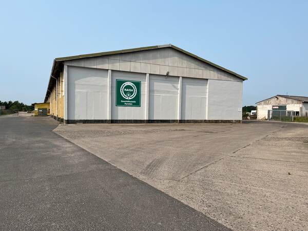 Du siehst eine Lagerhalle mit grünem RAISA-Schild und der Aufschrift Geschäftsstelle Parchim.